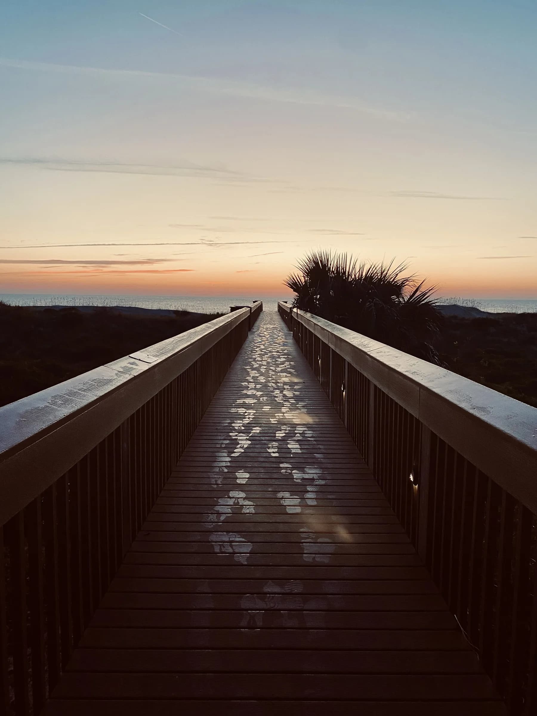 A wooden boardwalk running toward the sea at sunrise, from the photography gallery